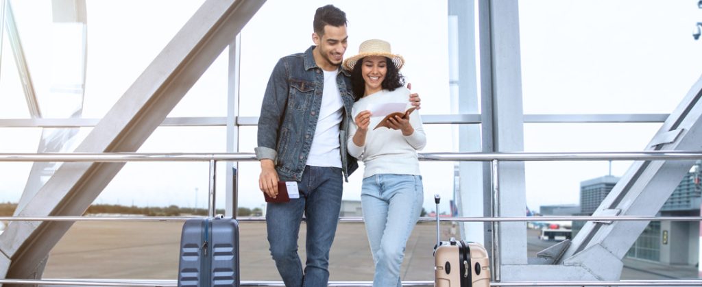 Smiling couple at airport with suitcases