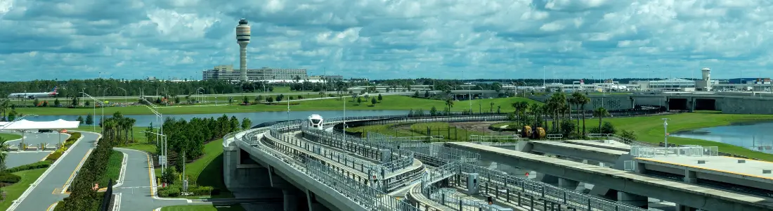 wide view of orlando international airport from a distance with control tower and cloudy sky