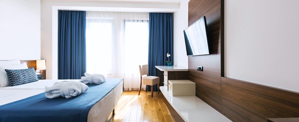 Interior of hotel room with king size bed, TV and desk