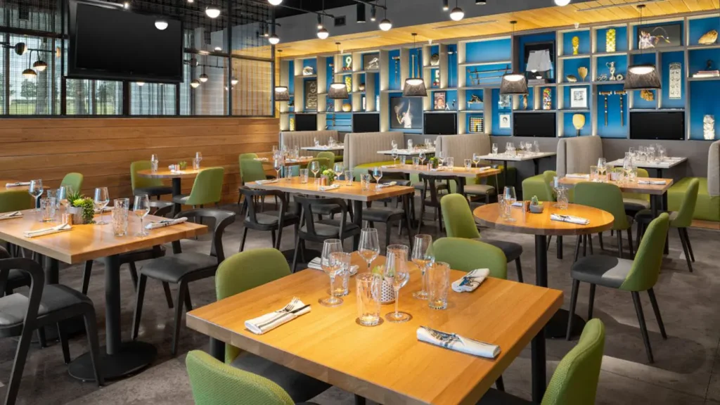 Tables set for dinner with green chairs at Tempo Restaurant at Aloft Orlando Lake Nona hotel